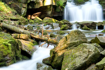 Obraz premium Górski wodospad, rzeka i głazy.