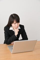 パソコンを使うビジネスウーマン、困る、怒る、悩む、指を顔に当てる