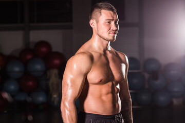 Fototapeta na wymiar Portrait of strong healthy handsome Athletic Man Fitness Model posing in gym
