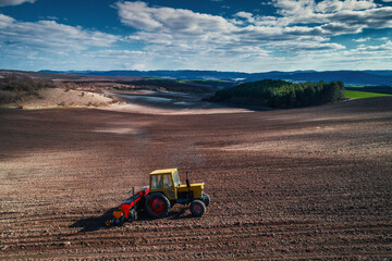 Obraz premium Aerial view of tractor working on the harvest field