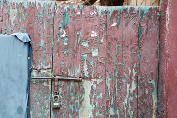 Alte sich auflösende rote Farbe an einer Tür mit Vorhängeschloss.