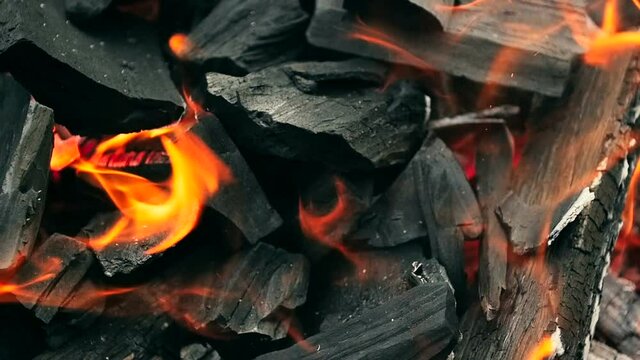 Closeup slow motion toned video of burning coal and wooden logs