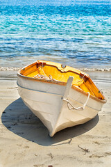 Wooden rowboat pulled up onto a sandy beach with the water in the background. Close up  - 157471644
