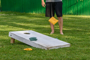 guy playing bags game out in backyard on sunny summer day