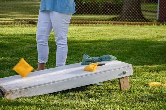 Playing Bags Game In Backyard At Summer Party