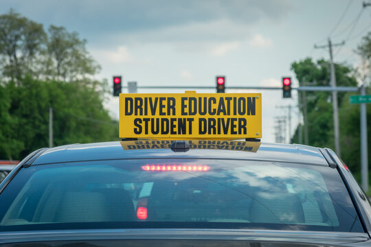 student driver sign on top of drivers ed car at stoplight