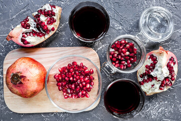 red pomegranate juice and sliced fruit on dark background top view