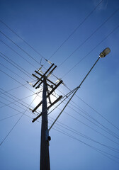 Power pole and lines with sun back lit.
