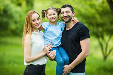 Obraz premium Happy young mother, father and daughter in summer park
