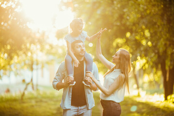 Happy family playing in nature late afternoon sunlight in the fall, summer. Mother, father and...