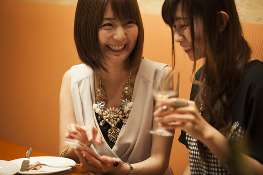 Women are watching smartphones while drinking white wine in the restaurant