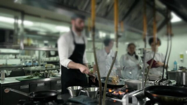 Chef is making flambe sauce on restaurant kitchen with onion and wine