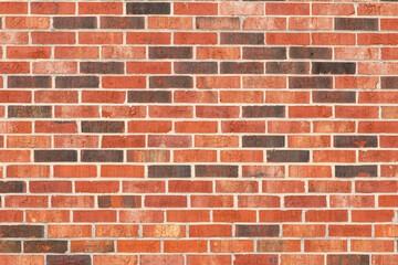 Brick wall with orange, red and brown bricks.