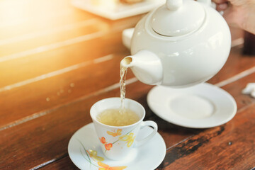 Time of Tea Break. Tea is pouring from teapot into a cup.