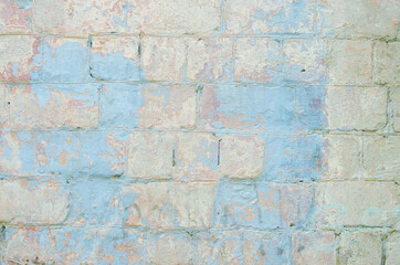 An old painted wall with a peeling blue paint from a large brick. Vintage texture. Red brick.