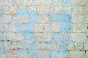 An old painted wall with a peeling blue paint from a large brick. Vintage texture. Red brick.