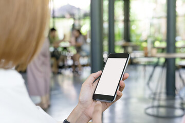 Close up of women's hands holding cell telephone with blank copy space scree for your advertising text message or promotional content with shop background.