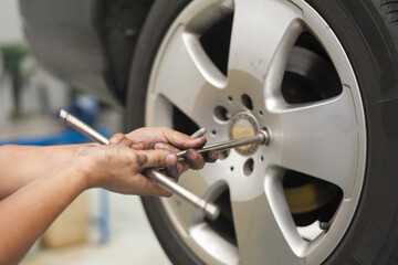 Hands of mechanic changing car wheel in auto repair service.