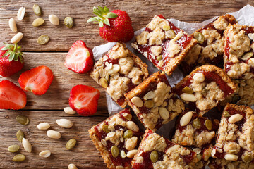 Oat bars with strawberries, seeds and nuts close-up on the table. horizontal top view
