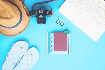 White laptop computer with woman accessories, camera and passport on blue color background, Summer travel concept