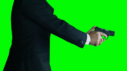 Businessman isolated on green screen. A man or killer in black suit with a black gun in and a red rose his hands.