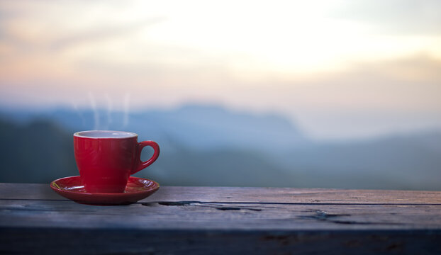 Red cup with coffee on table over mountains landscape with sunlight. Beauty nature background