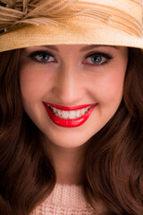 Close up portrait of a beautiful smiling young woman wearing a straw hat.