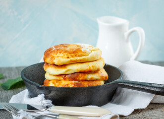 Homemade cottage cheese pancakes in a cast-iron frying pan. Russian dessert from cottage cheese.