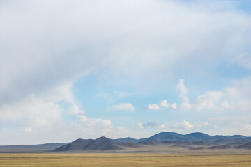 panoramic view of snow-capped mongolian prairie with cloudy sky on background
