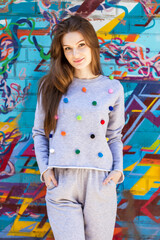 Fototapeta premium Hipster girl posing over wall,street style, sport,happy and positive girl,glam rock style,,natural long hair,beauty model face