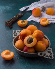 Vintage plate full of fresh apricots on blue background. Autumn or summer still life.