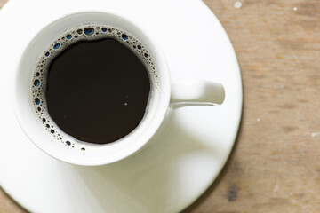 Top view of a cup of black coffee on wooden table
