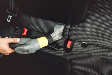 Close up details of car worker, vacuuming upholstery seats with steam cleaner