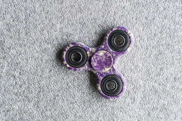 Fidget spinner purple colour stress relieving toy on grey.