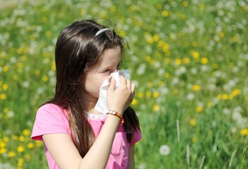 Little girl blows her nose with the handkerchief in the middle o