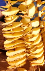 fried sliced potatoes stuck in the wooden skewer into the street
