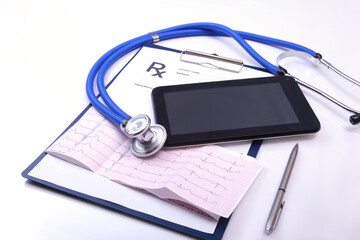 Closeup of stethoscope on a rx prescription, red heart and phone isolated on white background.