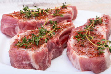 Raw pork chops, spices and rosemary on cutting board. Ready for cooking.
