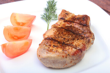grilled pork chop with vegetable on plate on wooden board