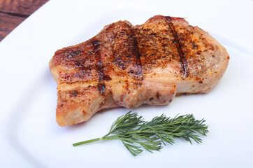 grilled pork chop on plate on wooden board