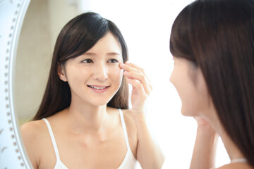 鏡を見て微笑む女性