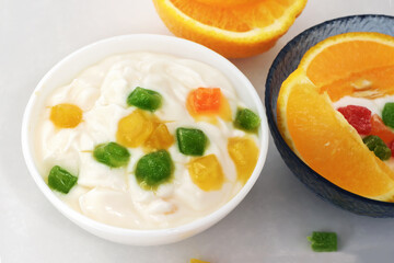 Yogurt with slices of fruit, orange slices and candied fruits on a white background