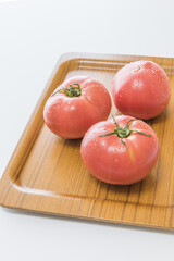 木のトレイの上の、水滴のついた新鮮なトマト