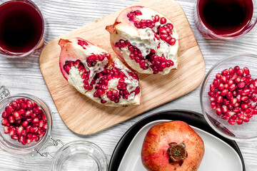 summer dessert with red juice and cut pomegranate on light wooden background top view