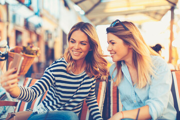 Two women friends taking a selfie in cafe