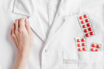 Medical equipment with overall and pills in doctor's office on white desk background top view