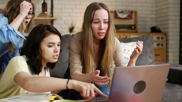 young female student becomes nervous and upset, because computer laptop breaks down and she loses everything, while studying seriously with friends together at home to prepare for difficult exam test