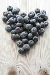 Blueberries in form of heart are on the wooden background