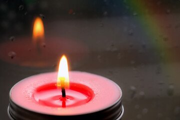 Vintage image of Light of Pink Candle in the front at window with blurred rain drops and low light nature background