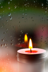 Vintage image of Light of Pink Candle in the front at window with blurred rain drops and low light nature background